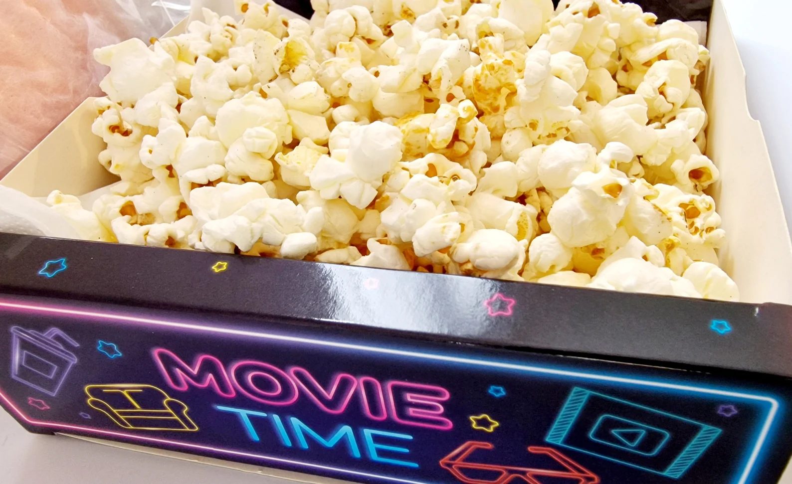 Close-up of a neon Movie Time snack tray heaped with popcorn