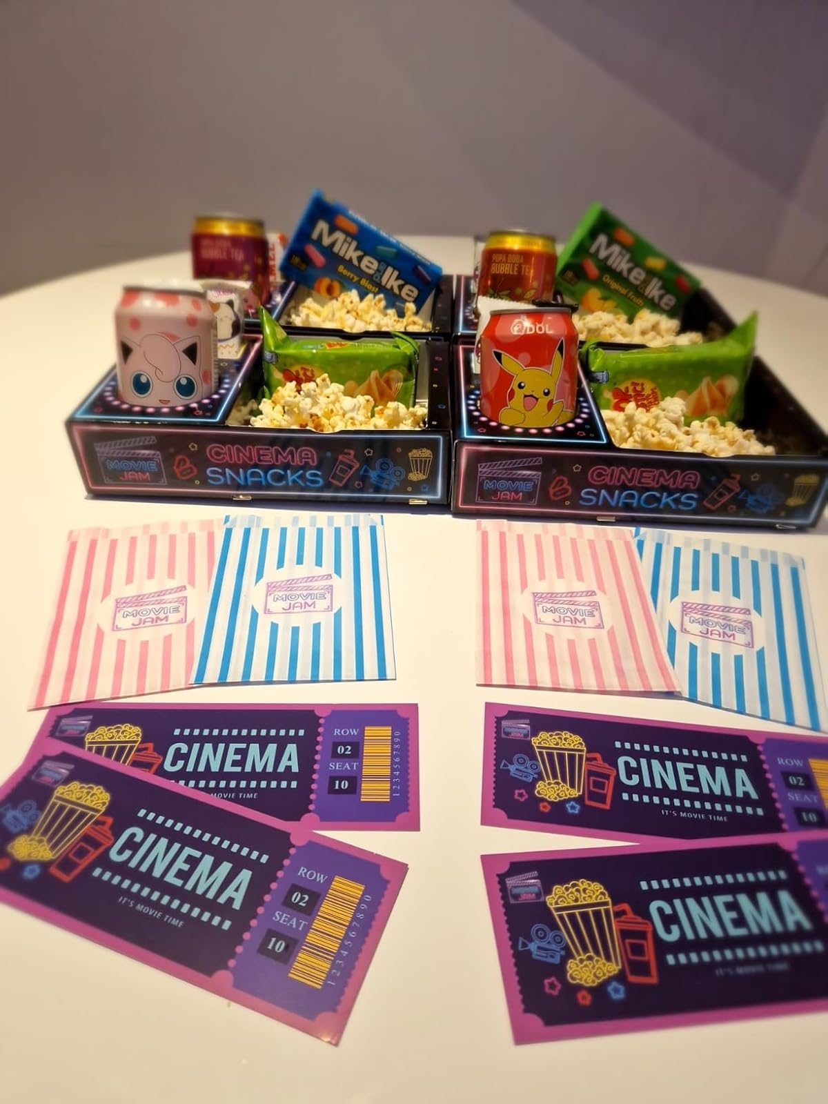 Flat lay of two filled neon snack trays with cinema tickets and striped sweet bags